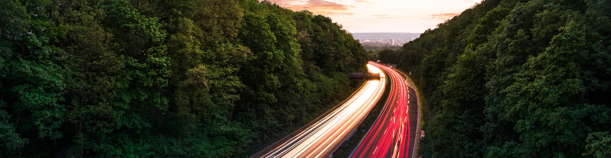 Road traffic next to forested area with sunrise | Seacon Logistics
