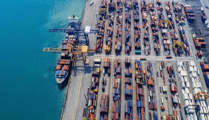 Container terminal from above, showing a container ship loading sea freight and moving trucks (road transport). | Seacon Logistics